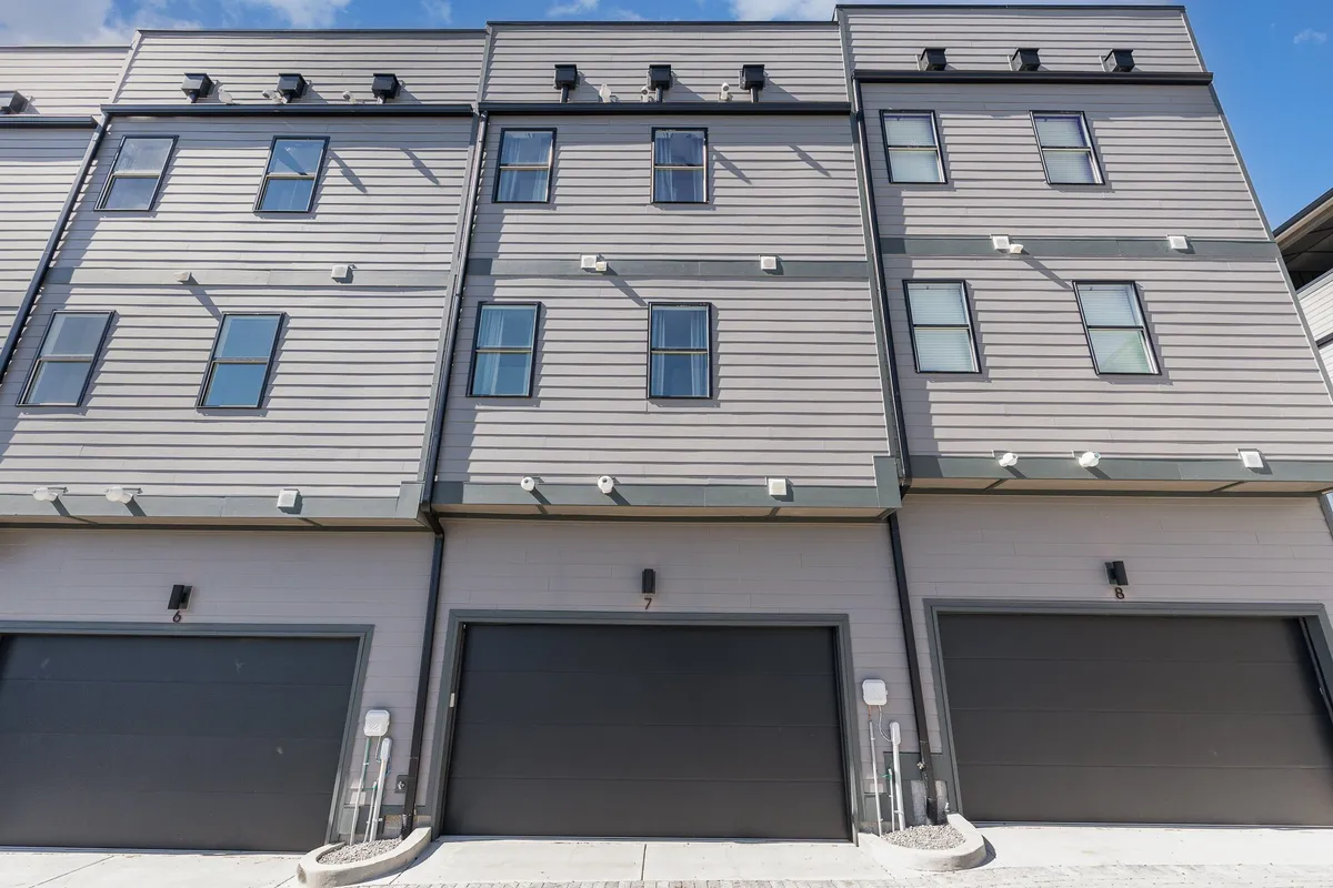 A contemporary exterior view of the property showcasing the modern architecture, two-car garage doors, large windows, and an inviting driveway suitable for parking multiple vehicles or gathering outdoors.